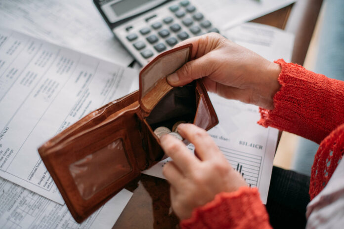 The hands of an elderly woman with an empty wallet and a lot of