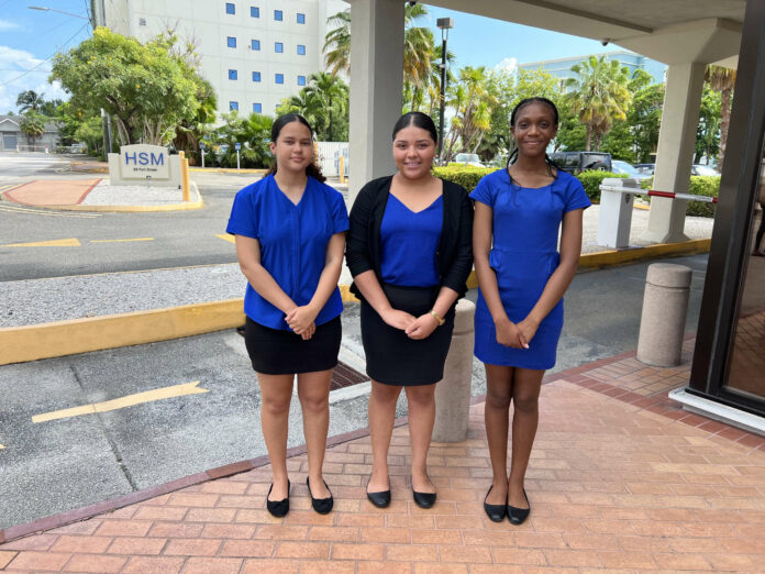 Kayleigh Bush, Jenae Whittaker and Phyllis Brown stand in front of HSM’s building on 68 Fort Street, George Town