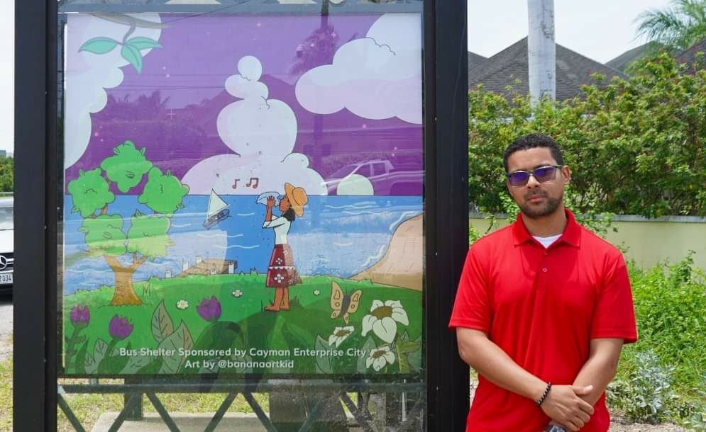 Caymanian digital artist Michael Mothen stands with his artwork at Rotary Central Bus Shelter. - Photos: Supplied
