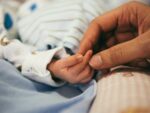Foster families see first stipend increase in years a parent holds a baby's hand, foster family