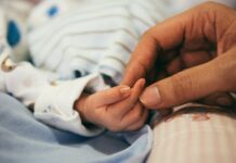 Foster families see first stipend increase in years a parent holds a baby's hand, foster family