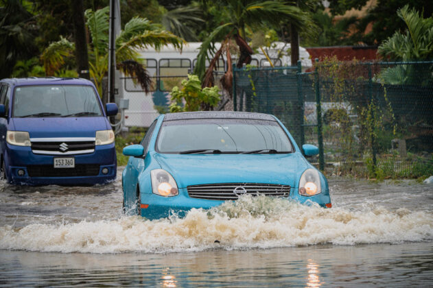 A car makes its way slowly through a flooded road. - Photo: Taneos Ramsay