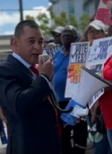 Honourable Joey Hew, Leader of the Opposition, using megaphone to speak to the people gathered outside Parliament