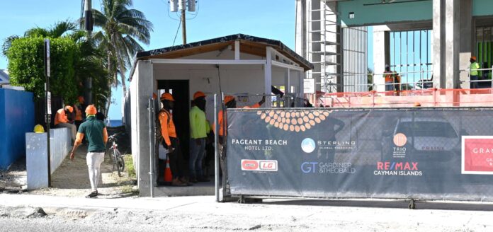 Workers stand outside the security checkpoint at the Hyatt Residences site on Tuesday. - Photo: Raymond Hainey