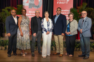 (iii)The Cayman First Board of Directors (L-R): Mr. Abraham Thoppil, Director; Mrs. Michele Fields, Director; Mr. Gordon Philip, Director; Ms. Alison Treco, Chair; Dr. Samir Mikhael; Mrs. Linda Goss, Director; Mr. Bryan Murphy, Director.

