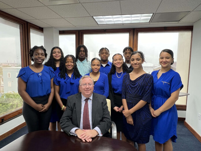 Huw Moses (HSM Managing Partner) seated in front of HSM interns. (L-R): Ahmoya Morrison, Nashla Evans McCoy, Shannell Pinnace Stewart, Alrick Peddie Jr, Rhynnia Rattary, Malachi Green, Samiya Wood, Jayden Nembhard, Azaria Ruiz-Bodden and Claudia Garcia Gurrero