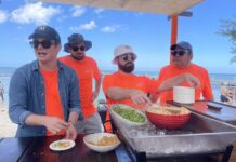 Chefs and guests celebrate culinary success of Cayman Cookout Chef Emeril Lagasse (r) serving at Beach Bash with his chef son EJ Lagasse (l) Cayman Cookout 2025
