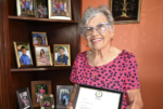 Cayman’s only living National Hero Francine E. Jackson humbled by honour Francine A. Jackson, standing next to her display of photos of her grandchildren at her West Bay home, shows her letter affirming her status as Cayman's new National Hero. - Photo: Reshma Ragoonath