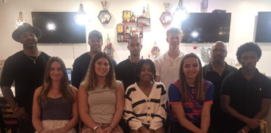 Back left, Olympic athletes Ronald Forbes and Jordan Crooks, along with seven Cayman youth athletes and former Sports Minister Bernie Bush, back right, at special dinner. - Photo: Supplied