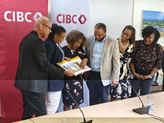 CIBC executives and managers look at the coffee table book 'Unsung Heroes of the Caribbean', featuring past winners of the bank’s Unsung Heroes programme. - Photo: Supplied