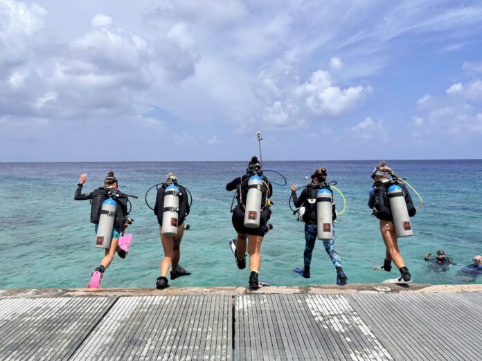 Divers jump into the water off the pier at Lighthouse Point in West Bay for Women's Dive Day. - Photo: Lisa Collins, Cayman Capture Ltd.
