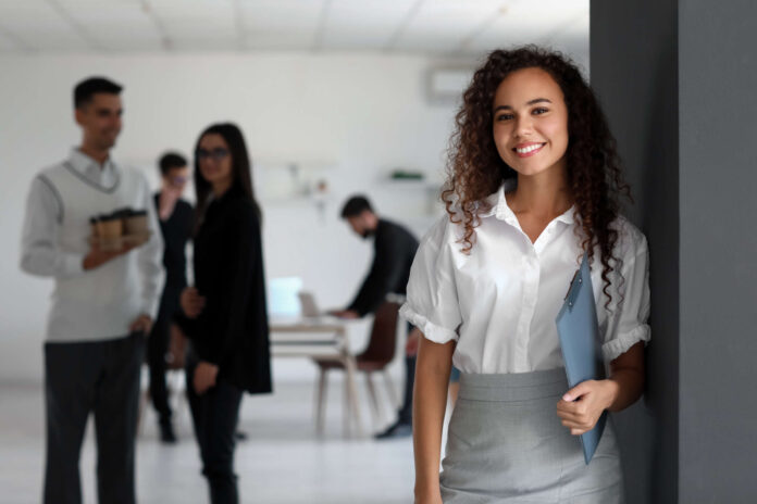 Young African-American woman with clipboard in office